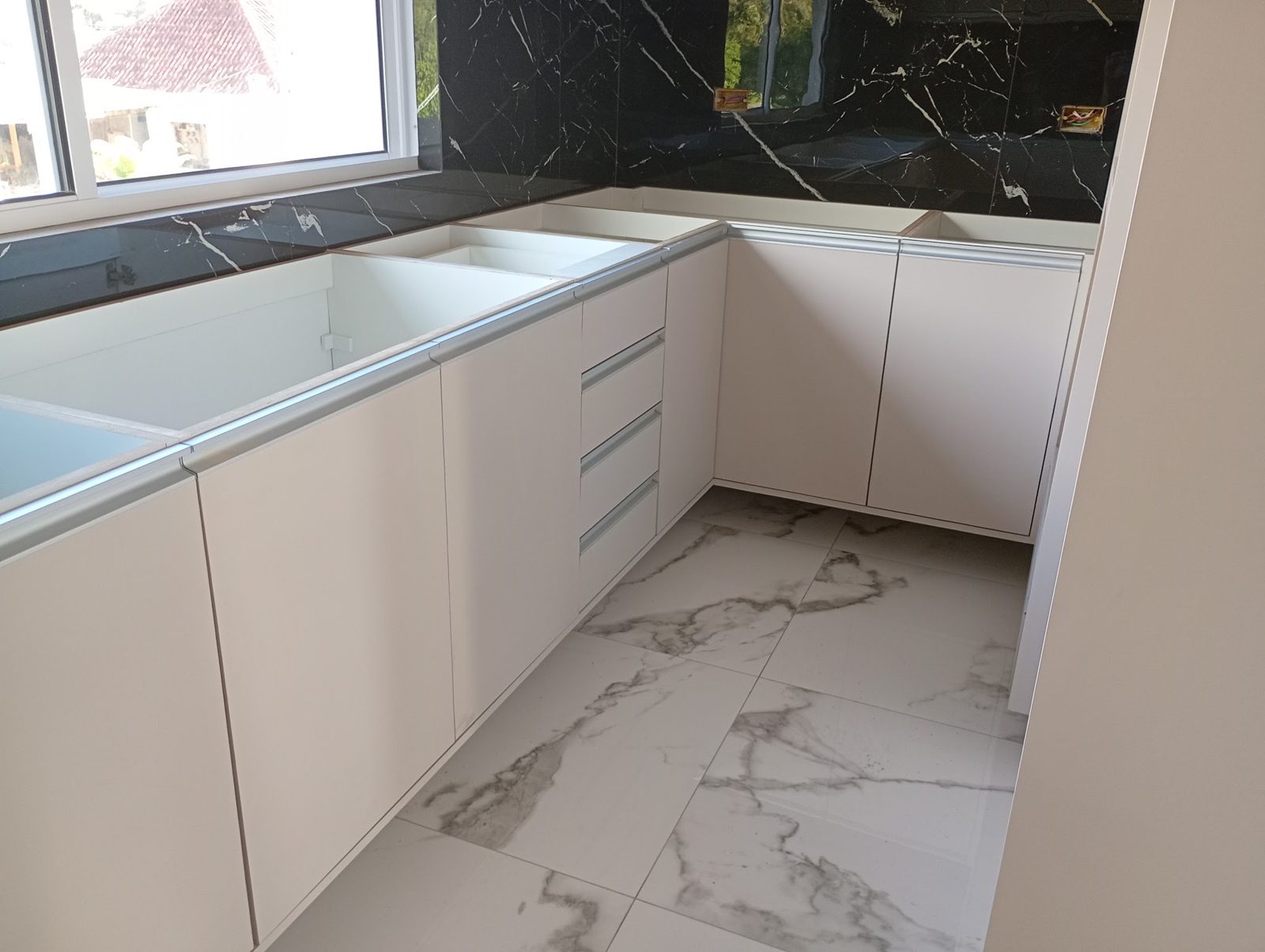 Cozinha planejada em MDF branco com bancada e revestimento em mármore