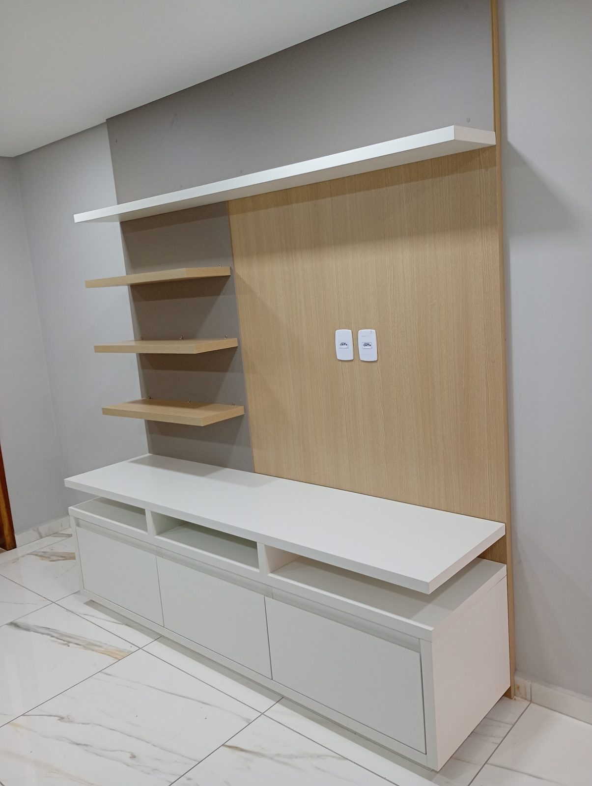 Painel de TV planejado em madeira com prateleiras e balcão branco